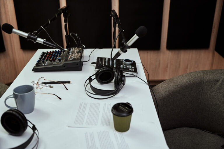 Working place of radio host. Close up of microphones, headphones, sound mixing desk, script on the table in recording studio or broadcast room